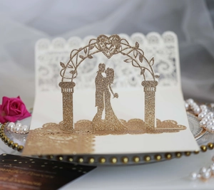 Detailed laser-cut 3D pop-up wedding invitation featuring couples under a glitter arch