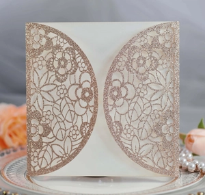 Close-up of laser-cut floral pattern on rose gold glitter wedding invitation card