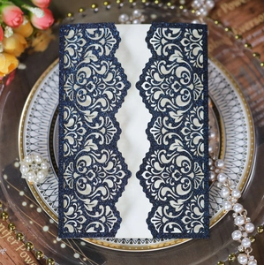 Detail of laser cut navy blue glitter wedding invitation with intricate lace design
