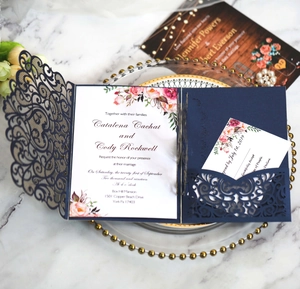 Détail de faire-part de mariage bleu marine découpé au laser avec carte florale rose