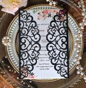 Close-up of laser-cut glitter wedding invitation with floral card and pearl decoration