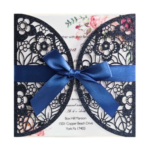 Detail of navy blue glitter laser-cut wedding invitation with elegant silk ribbon bow