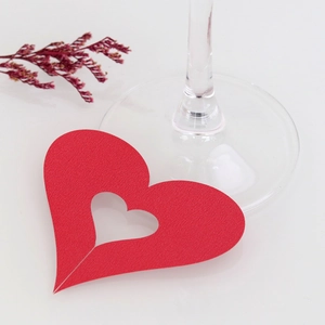 Detail of red heart-shaped laser-cut place card with hollow design for wedding glasses