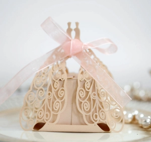 Detail of laser-cut peacock pattern gift box with pink organza ribbon on a white plate