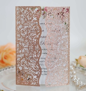 Detail of rose gold glitter laser-cut wedding invitation with floral insert and elegant props