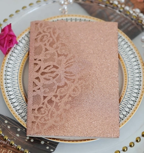 Détail du motif floral découpé au laser sur une invitation de mariage à paillettes or rose