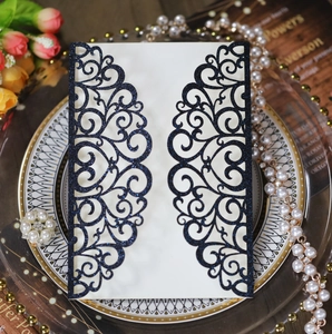 Intricate laser-cut navy blue wedding invitation with glitter texture and floral scrolls