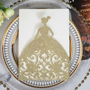 Close-up of golden glitter wedding invitation with laser-cut floral gown silhouette