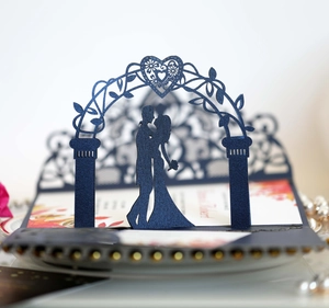 Detail of 3D laser cut navy blue wedding invitation showing romantic couple silhouette