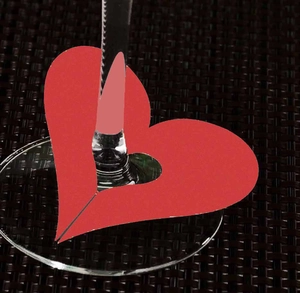 Detail of red heart laser-cut paper wine glass marker with central ring cutout