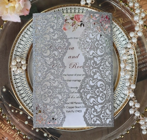 Detailed laser-cut silver glitter wedding invitation with elegant hollow-out pattern