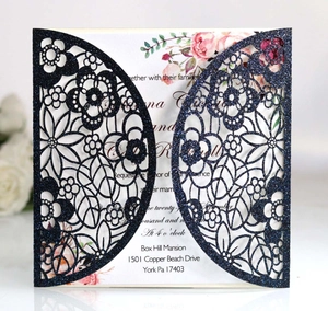 Close-up of laser-cut navy blue glitter invitation with elegant floral lace details