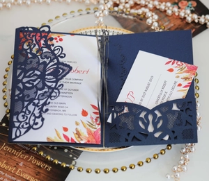 Detail view of navy blue laser-cut wedding invitation set with floral design and RSVP card