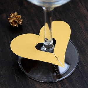Detail view of a laser-cut gold heart-shaped place card on a wine glass rim