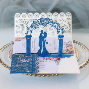 Detail of 3D laser cut wedding invitation with blue glitter silhouette and lace patterns