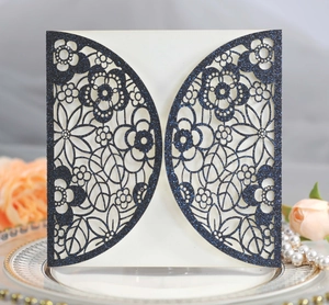Detail of laser cut navy blue glitter wedding invitation with floral hollow patterns