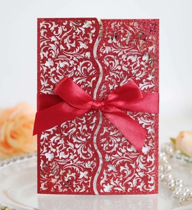 Macro detail of red glitter laser-cut wedding invitation with elegant satin bow