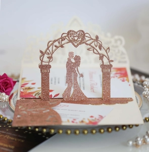 Détail macro du faire-part de mariage 3D or rose avec paillettes et silhouette découpée