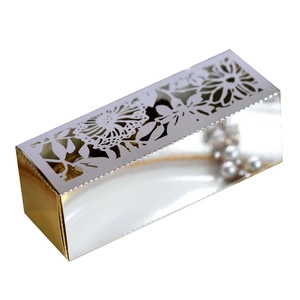 Macro detail of silver laser-cut floral patterns on a luxury metallic wedding favor box