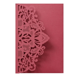 Detail of laser-cut burgundy wedding invitation cover with intricate floral lace patterns