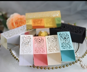 Laser cut rose candy boxes for weddings in assorted colors on a decorative glass tray