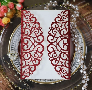 Detail of red laser-cut wedding invitation with glitter finish and heart patterns