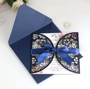 Detailed laser-cut navy blue wedding invitation with silk bow and floral insert card