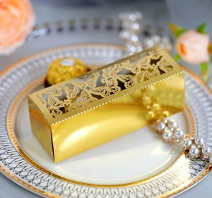 Macro view of gold laser-cut candy box with intricate butterfly patterns on gold tray