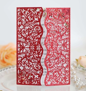 Detailed laser-cut glitter wedding invitation with ornate red floral vine patterns