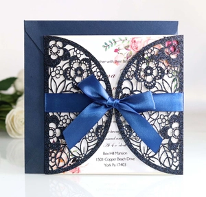 Detail of laser cut navy glitter wedding invitation with blue ribbon and floral inner card