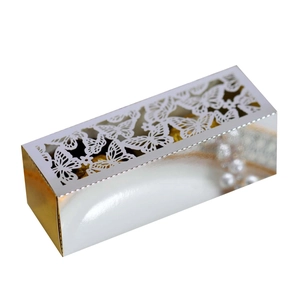 Detail of silver metallic gift box with white laser-cut butterfly pattern and gold candies