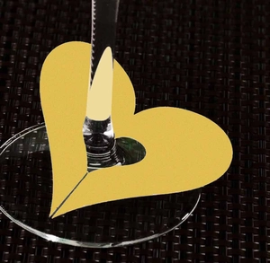 Detail of yellow hollow heart-shaped paper place card for wine glass base decoration