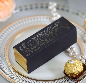 Detail of laser-cut black gift box with gold liner on decorative porcelain plate