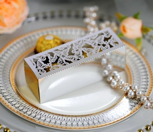 Macro view of gold laser-cut butterfly candy box on a vintage plate with pearls