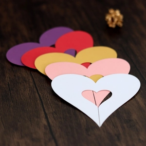 Macro detail of heart-shaped hollow paper cards in various colors on wooden surface