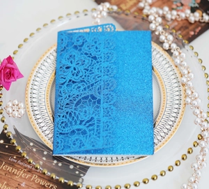 Detail of dark blue glitter wedding card with laser-cut floral lace on white porcelain