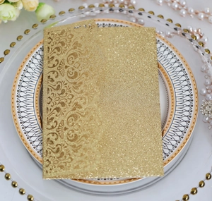 Detail of laser-cut glitter wedding invitation with European scroll patterns on a ceramic plate