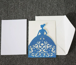 Detail of laser-cut wedding invitation featuring blue glitter gown and white insert card