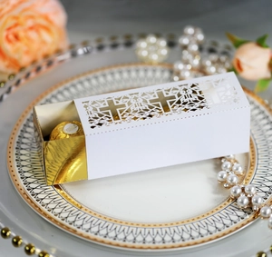 Detail view of laser-cut white cross favor box with gold insert and chocolate interior
