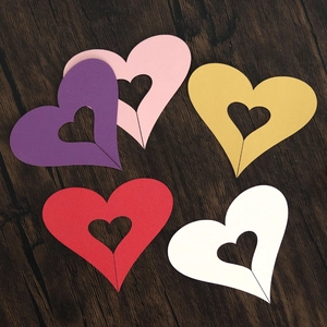 Detailed view of hollow heart-shaped paper cards in various colors on wooden background