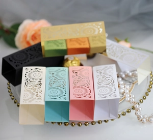 Laser cut hollow flower candy gift boxes in assorted colors displayed on a gold tray