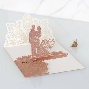 Dettaglio macro del pizzo tagliato al laser e biglietto di nozze 3D con glitter oro rosa