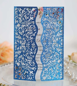 Detail of laser-cut blue glitter wedding invitation with elegant floral hollow texture