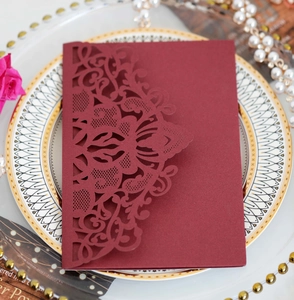 Macro shot of burgundy laser-cut wedding invitation with elegant floral lace patterns