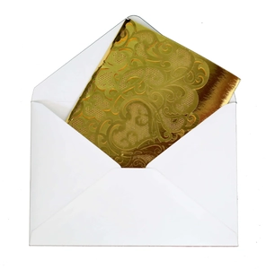 Détail du motif floral découpé au laser sur invitation dorée avec enveloppe blanche