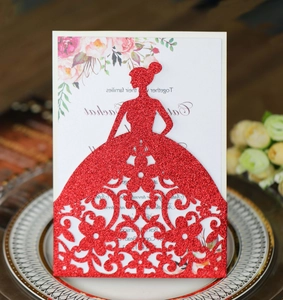 Close-up of red glitter laser-cut wedding invitation featuring a hollow dress silhouette