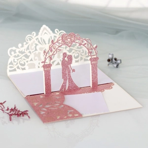 Détail macro de l'invitation de mariage 3D découpée au laser avec paillettes roses et couple