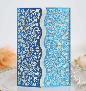 Close-up of glittery blue laser-cut invitation card with floral patterns and pearl decor