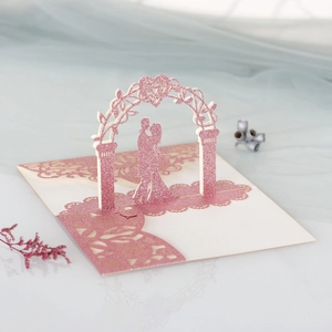 Carte de mariage 3D découpée au laser montrant un couple sous une arche de fleurs à paillettes