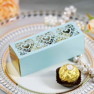 Detail of light blue laser-cut heart favor box with gold trim on a white plate